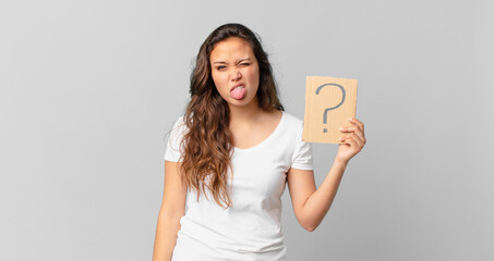 young pretty woman feeling disgusted and irritated and tongue out and holding a question mark sign