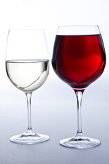 Due bicchieri di vino: un bicchiere di vino bianco e un bicchiere di vino rosso su sfondo bianco.