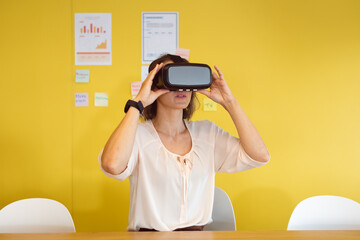 Caucasian woman sitting at desk using vr headset at work