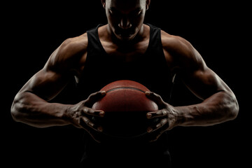 Basketball player holding a ball against black background. Serious concentrated african american man