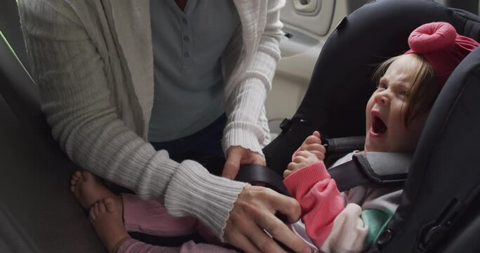 Mid section of caucasian mother keeping her baby in safety seat in the car