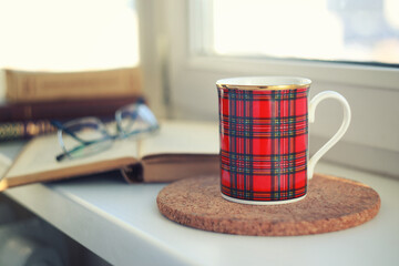 Cup of coffee, books and glasses on windowsill. Morning tea or coffee. Cosiness and good morning concept