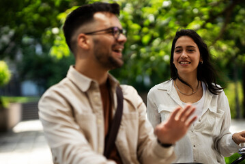 Happy funny couple with bicycle in the park. Loving couple enjoying together outdoors.