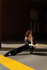 Portrait of young girl with curly hair and red lips posing on steer on building background