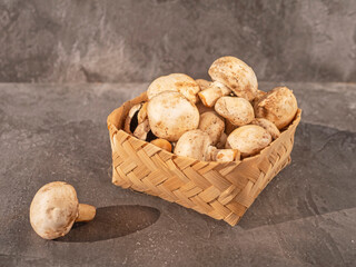 Champignon mushrooms in basket on gray background