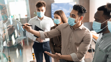 Team in masks having meeting using sticky post-it notes