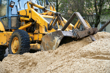 tractor or bulldozer works with a pile of sand for construction