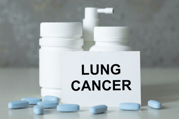 Card with text LUNG CANCER next to white medicine jars on the table, medical concept