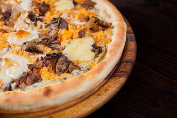 Pizza with cheese and mushrooms on a wooden plate. Close-up, selective focus
