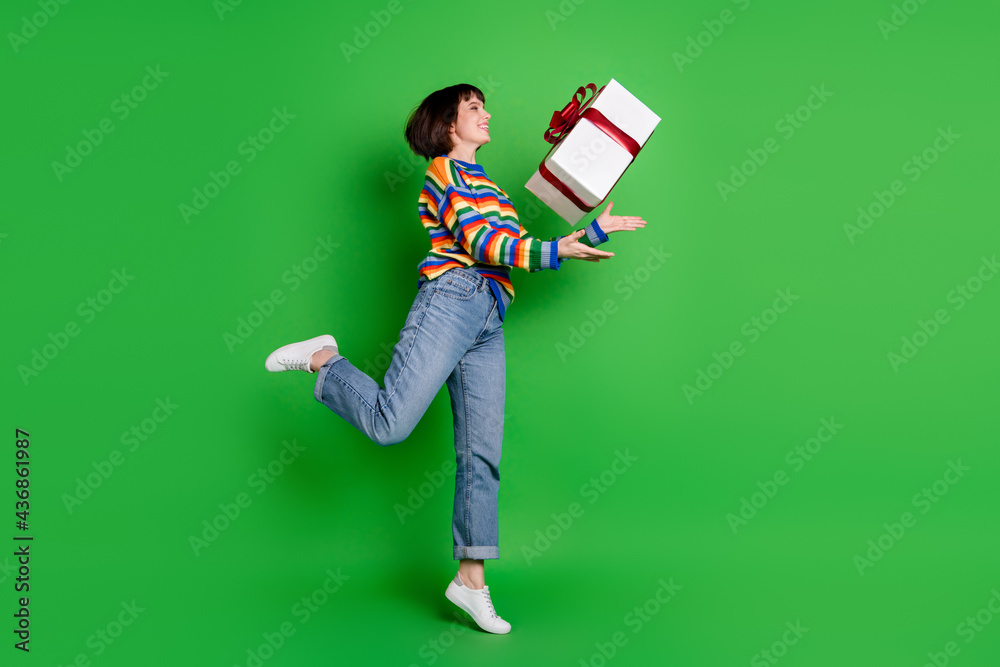 Poster Full length photo shiny excited lady dressed colorful pullover jumping high catching big present box isolated green color background