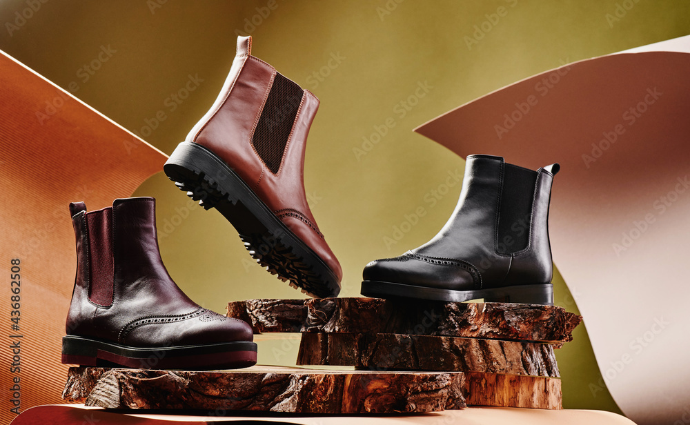 Wall mural Black and brown leather chelsea boots made of genuine leather in classic style on a wooden cut. Close-up. High quality photo