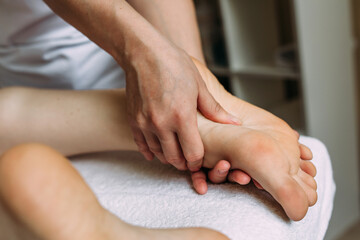 Fototapeta na wymiar The masseur gives a massage to the female feet at the spa.