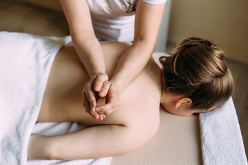 Massage therapist doing massage on the female body in the spa.