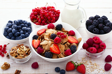 Berries and granola in plate with milk on wooden desk