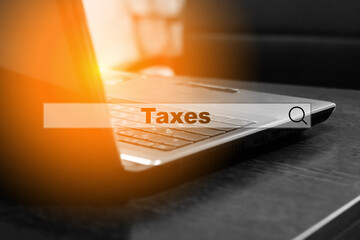 Financial word - Tax, on a hologram on the background of an open laptop at home. Tax time and interest concept