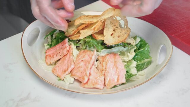 Chef cooking Caesar salad with grilled chicken