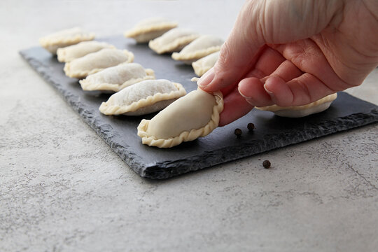 Close up hand taking raw dampling on a black stone board.