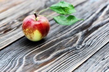 Fresh ripe apple with green leaves on wooden table
