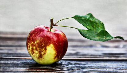 Fresh yellow-red apple with green leaves on wooden table