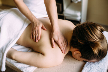 Massage therapist doing massage on the female body in the spa.