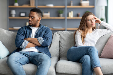 Relationship Crisis. Offended Interracial Couple Sitting On Couch After Quarrel