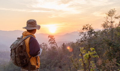 Hipster male hiker with backpack enjoying sunset on peak mountain. Tourist traveler on background view mockup.