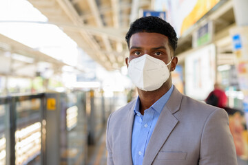 Fototapeta na wymiar Portrait of African businessman at train station platform wearing face mask