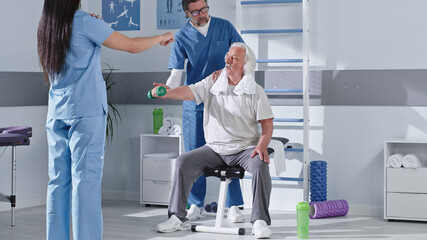 Male and female doctors showing rehabilitation exercise to elderly patient