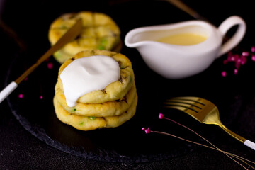 Cheesecakes with sour cream on a black background. A plate of slate. Condensed milk