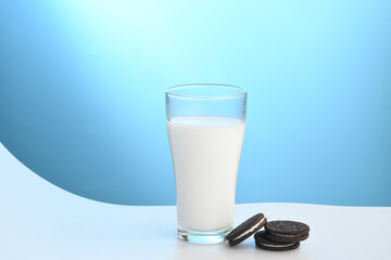 Pouring a glass of milk on a white table on a blue background, nutritious and healthy dairy products concept.