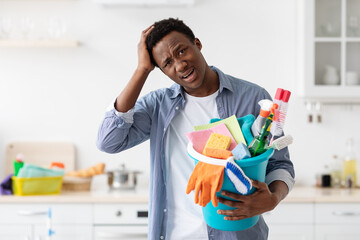 Confused black guy holding busket with cleaning tools