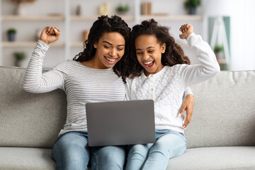 Excited african american mother and daughter with laptop