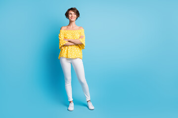 Full size photo of dreamy curious young woman folded hands look stand empty space isolated on blue color background