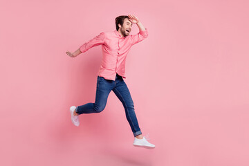 Fototapeta na wymiar Full length body size view of attractive cheerful guy jumping walking seeking news isolated over pink pastel color background