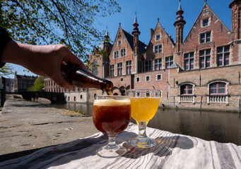 Obraz premium Tasting of Belgian beer on open cafe or bistro terrace with view on medieval houses and canals in Bruges, Belgium