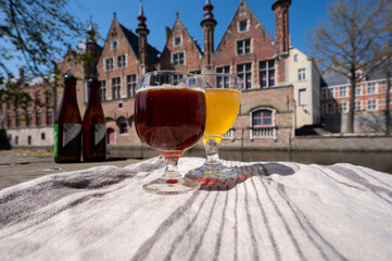 Naklejka premium Tasting of Belgian beer on open cafe or bistro terrace with view on medieval houses and canals in Bruges, Belgium