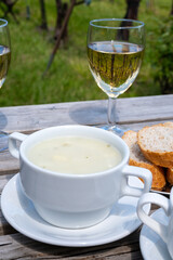 Lunch with homemade white asparagus soup and Dutch white wine served outdoor on green meadow with vineyard, asparagus and wine production farm in Netherlands