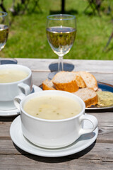 Lunch with homemade white asparagus soup and Dutch white wine served outdoor on green meadow with vineyard, asparagus and wine production farm in Netherlands