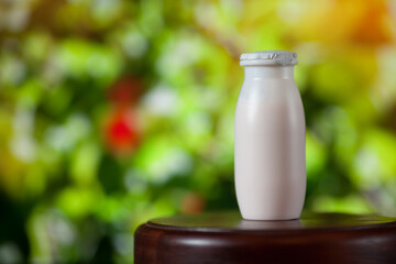 Natural liquid yogurt with probiotics in small plastic bottles on wooden table on background of green trees on a sunny day. Healthy, balanced diet food, healthy breakfast, dairy products.