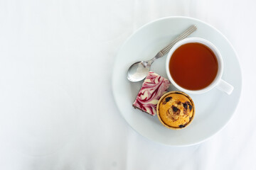 Obraz na płótnie Canvas cup of tea with cake on white tablecloth