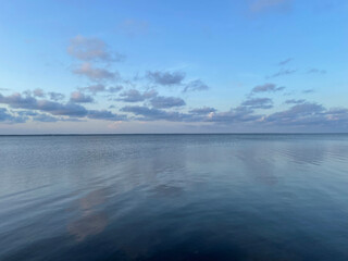 sunset clouds reflecting onto still bay water 