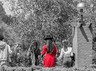Girl with a red coat and a black hat walking in the park. Selective color.