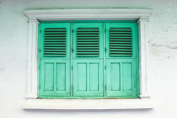 Antique wooden window frame, turquoise windows and the white Wall
