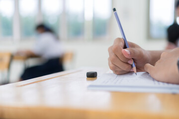 Girl Student in exam test school, Side View of high school or university holding writing document paper answer sheet and lecture final exams in classroom with white uniform pupil of Thailand