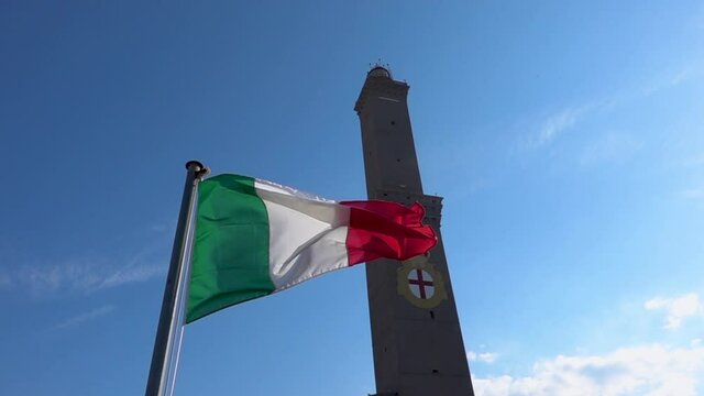 The Italian flag flying near Genoa ancient lighthouse Lanterna in Italy. Slow motion.