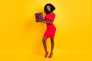 Full size photo of excited charming dark skin girl hold giftbox open mouth wear stilettos isolated...