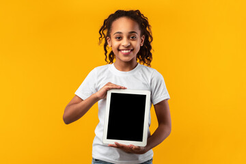 Smiling black girl showing blank tablet screen