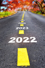 Happy new year concept and business beginning with challenge  idea. Journey to new year 2022 to 2025 on asphalt road surface with autumn season