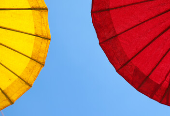 Yellow and red handmade paper umbrellas with blue sky.