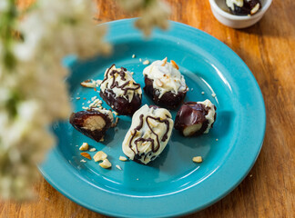 Homemade date candies with nuts, covered with white chocolate and decorated with chopped nuts.